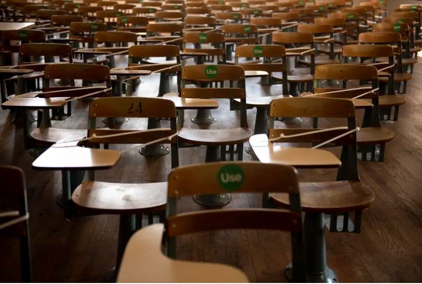 Desks are zip-tied and a green "Use" sticker is placed on available desks to practice social distancing in an academic hall at the University of Texas at Austin on Aug. 24, 2020.